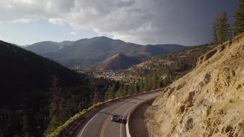 Car Drives down a Mountain Road Toward Town Stock Footage 244265822