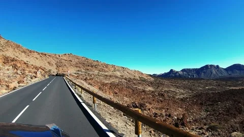 The car drives on flat road through desert. Hills are visible in distance. There Vídeo Stock 156790928