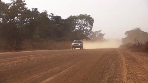 A car drives, kicking up dust on a broken dirt road in Africa Stock Footage 258951466