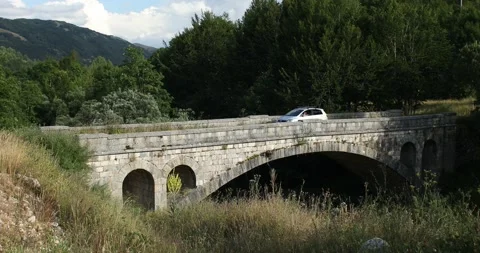 A car drives over an old stone bridge in a mountain village in montenegro. Stock Footage 247715463