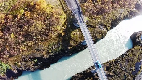 Car drives over roaring river in Iceland, slow motion aerial Stock Footage 75203029
