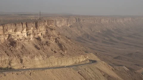 Car drives past dramatic ridge of Makhtesh Ramon, crater in Israel Stock Footage 168771747
