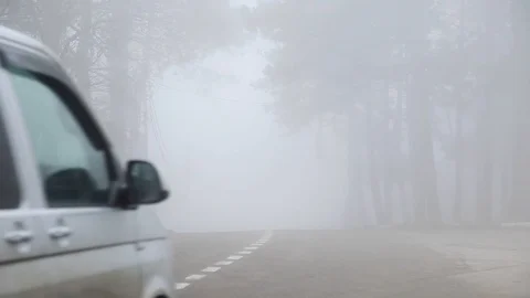 Car drives past in very heavy fog in forest. concept of poor visibility on roads Stock Footage 122705341