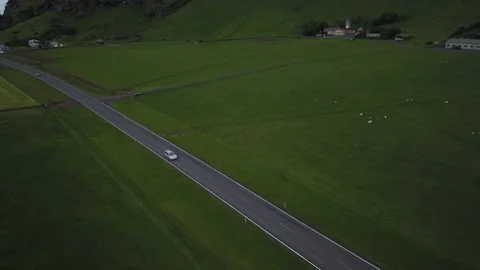 Car drives on remote road next to fields Stock Footage 166866745