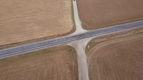 Car drives to a rural suburban intersection among the cereal wheat fields Stock Footage 94032142