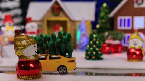 A car drives up to a snowman against the backdrop of a small Christmas town Stock Footage 340886018