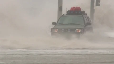 A car drives through deep water during flooding from a massive storm or Stock-Footage 73240750