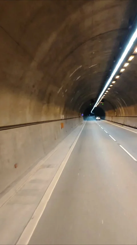 Car drives through a long well lit highway tunnel Video stock 331980103