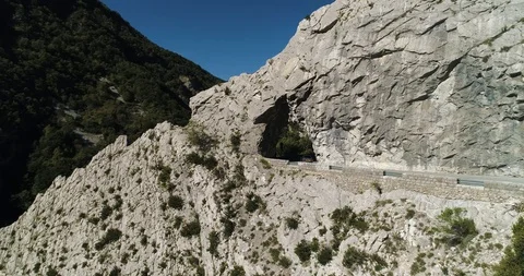 Car drives through man made tunnel in rock face in Pyrenees drone aerial 4k Stock Footage 125755080