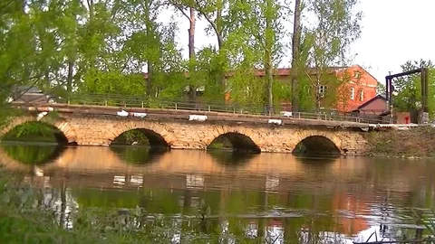 Car drives through the old stone bridge across the river Stock Footage 75789419
