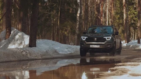 A car drives through a puddle, an SUV drives through a forest 库存影片 330767037