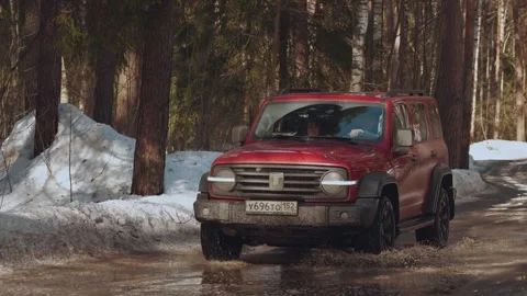 A car drives through a puddle, an SUV drives through a forest Vidéo 330767046
