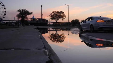 Car Drives through refelctive Flooded Road at Sunset Stockbeeldmateriaal 104889785