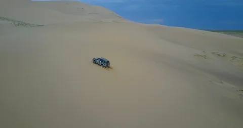 Car drives to the top of a sand dune in the Gobi desert in Mongolia Stock Footage 121503239