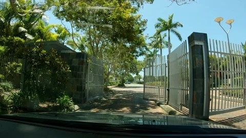 Car drives trough automatic security gate on a palm tree lined road Stock Footage 100798968