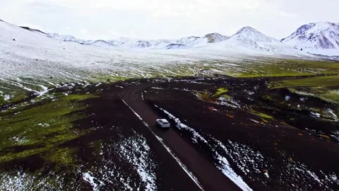 Car drives on winding road through snowy Icelandic landscape. Stock-Footage 341068525