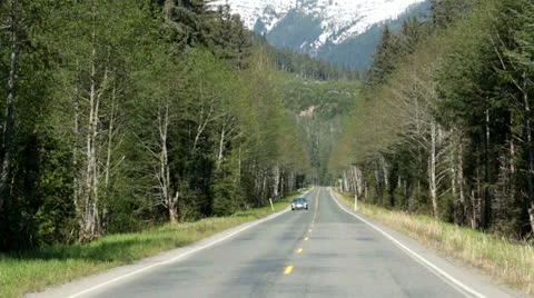 Car driving on Alaskan forest road towards camera HD 7098 Stock Footage 24743058