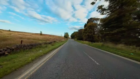 Car driving along empty countryside road surrounded by fields and trees POV Vidéo 339344571