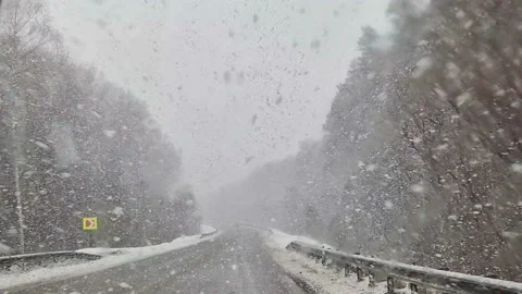 The car is driving along the highway through snow and blizzard. Video through Stock Footage 178364942