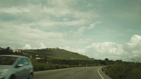 Car driving along road - Car passing by trees - clouds in the sky - Slowmotion Video stock 80383653
