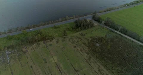 Car driving alongside a large river at sunset Stock Footage 110889677