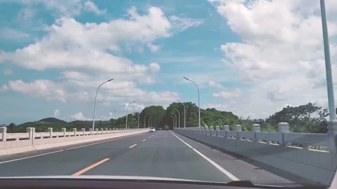 The car is driving on a bridge under a beautiful blue sky and white clouds Stock Footage 157218366