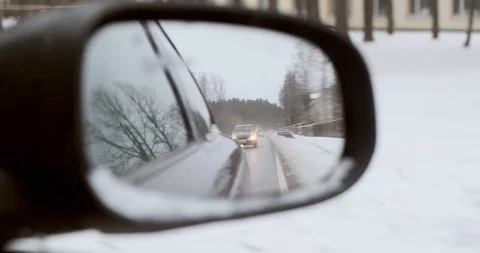Car driving in a car mirror reflection during winter and a blizzard in DCI 4K Stock Footage 104552042