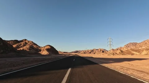 Car driving on desert highway between rocky mountains during sunset light Stock-Footage 327434666