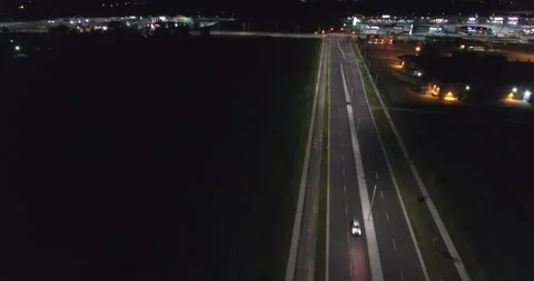Car Driving Down Empty Road At Night From Shopping Plaza Stock Footage 248072372