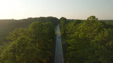 Car Driving Down Empty Rural Road in the Country at Sunset Stockbeeldmateriaal 248236576