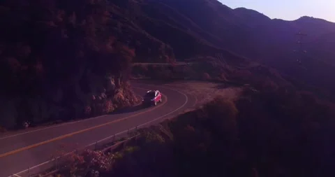 Car driving down empty winding road in the mountains Stock Footage 136337548