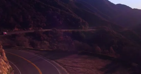 Car driving down empty winding road in the mountains Stock Footage 136337576