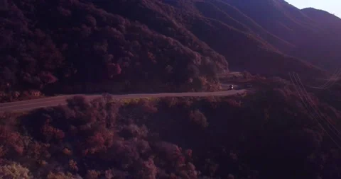 Car driving down empty winding road in the mountains Stock Footage 136337750