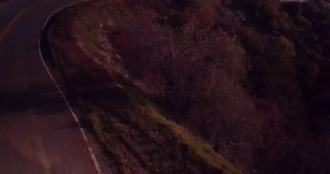 Car driving down empty winding road in the mountains Stock Footage 136337930