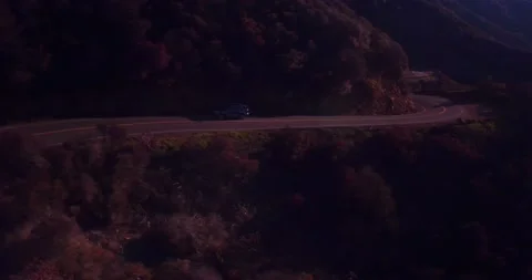 Car driving down empty winding road in the mountains Stock Footage 136338835