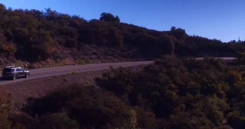 Car driving down empty winding road in the mountains Stock Footage 136341303