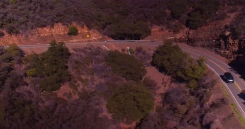 Car driving down empty winding road in the mountains Stock Footage 136341403