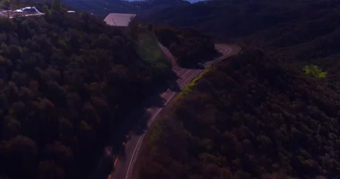 Car driving down empty winding road in the mountains Stock Footage 136341449