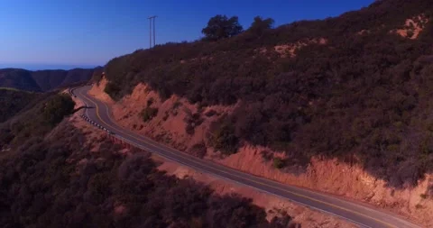 Car driving down empty winding road in the mountains Stock Footage 136341509