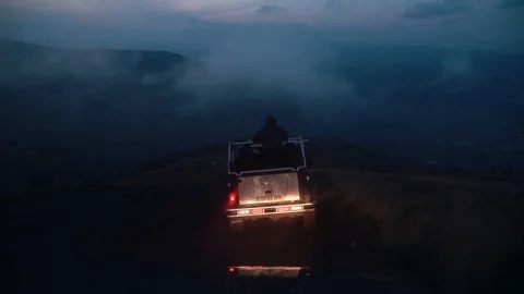 Car driving down in moody clouds and fog roll over green mountain tops on a Stock Footage 119769507