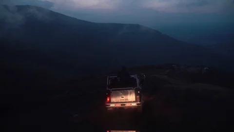Car driving down in moody clouds and fog roll over green mountain tops on a Stock Footage 119769545
