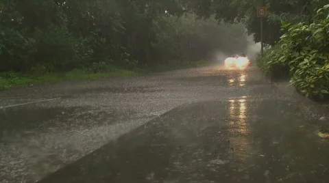 Car driving down partially flooded road in heavy rain Stock Footage 503660