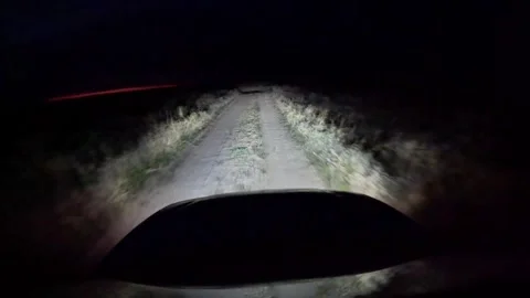 A car is driving down a road at night with a bright light shining on it Stock Footage 313082771