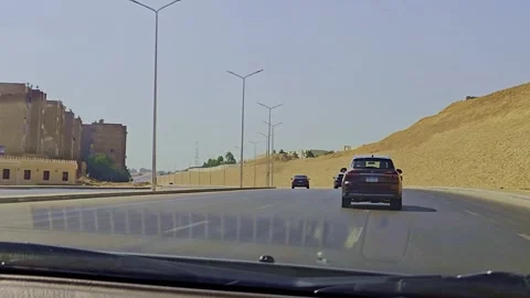 A car driving down a road with a wind turbine in the background Vídeo Stock 291584000