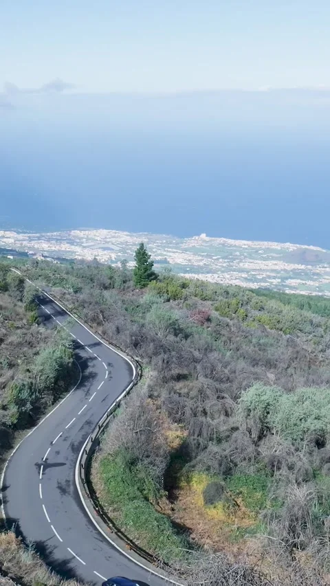 Car driving down a winding mountain road near the ocean Stockbeeldmateriaal 329865302