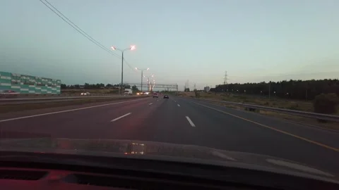Car Driving At Dusk Down Tree-Lined Road With Headlights On Seen Through Windshi Vídeos de archivo 335448543
