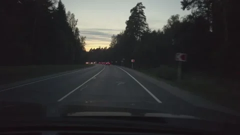 Car Driving At Dusk Down Tree-Lined Road With Headlights On Seen Through Windshi 스톡 동영상 335448708