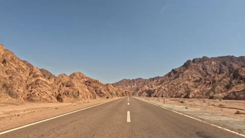Car driving on empty desert asphalt road between mountains with clear blue sky Stock Footage 340870560