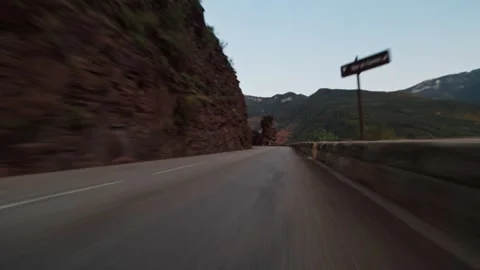 Car driving fast along a winding mountain road, showing speed and travel Vídeos de archivo 341958398