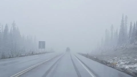 Car driving with heavy snow in blizzard with poor visibility at national park Stock Footage 166095258